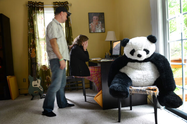 Jackie Barden is sitting at a desk with her face in her hands; Mark Barden puts his hand on her shoulder